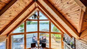 A wooden interior with a large window overlooking a deck and lake. - Lakefront Lake Anna Log Cabin, Views, Dock, Deck (Bumpass)