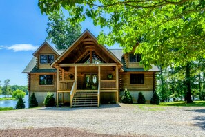 A log cabin with a front porch, a chimney, and a view of a lake. - Lakefront Lake Anna Log Cabin, Views, Dock, Deck (Bumpass)