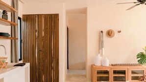 A modern living room with a wooden door, a white sofa, a wooden cabinet, and a ceiling fan. - Chic Beach suite with Plunge Pool in Tulum Hotel Zone (Tulum)