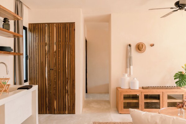 A modern living room with a wooden door, a white sofa, a wooden cabinet, and a ceiling fan. - Chic Beach suite with Plunge Pool in Tulum Hotel Zone (Tulum)