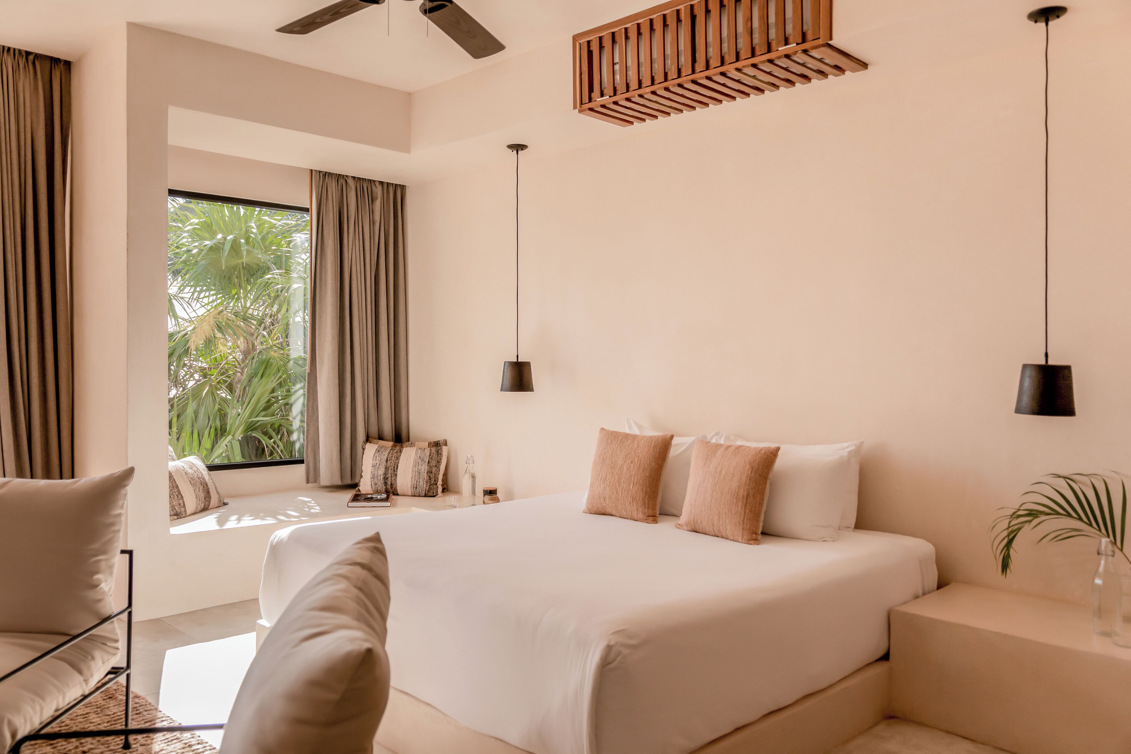 A modern bedroom with a large bed, a ceiling fan, and a window with curtains.
