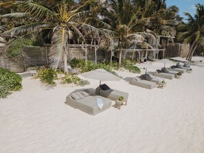 A beachside lounge area with sun loungers, umbrellas, and palm trees. - Chic Beach suite with Plunge Pool in Tulum Hotel Zone (Tulum)