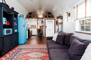 A living room with a dark sofa, a blue refrigerator, and a patterned rug. - Near Lazy E Edmond Guthrie Amenity Packed (Edmond)