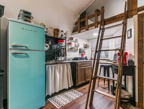 A kitchen with a teal refrigerator, wooden ladder, and a window overlooking the room. - Central OK Escape or Rodeo Basecamp near Lazy E Amenity Packed (Edmond)