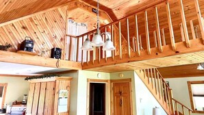 Un interior de madera con techo alto, una escalera y un candelabro colgante.