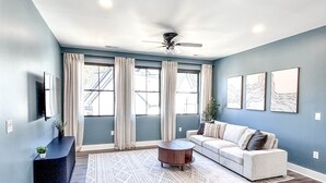 A living room with a sofa, a coffee table, a floor lamp, and a ceiling fan. - Luxury Guest House w/Resort Style Pool & Spa, pets welcome (Huntersville)