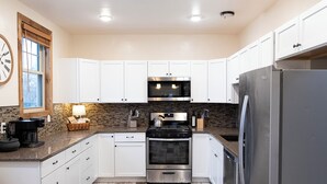 A modern kitchen with white cabinets, stainless steel appliances, and a herringbone-patterned floor. - Matilda - Stunning, 3-bed, vintage home in Duluth! (Duluth)