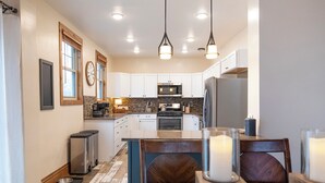 A modern kitchen with white cabinets, a central island, and pendant lighting. - Matilda - Stunning, 3-bed, vintage home in Duluth! (Duluth)