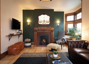 A living room with a fireplace, a television, and a comfortable seating area. - Matilda - Stunning, 3-bed, vintage home in Duluth! (Duluth)