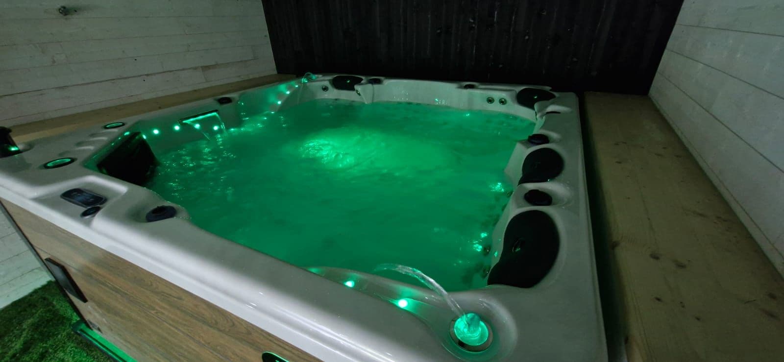 A hot tub with a rectangular shape, multiple jets, and green lighting.