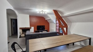 Un salon moderne avec un canapé, une table à manger en bois et un téléviseur.