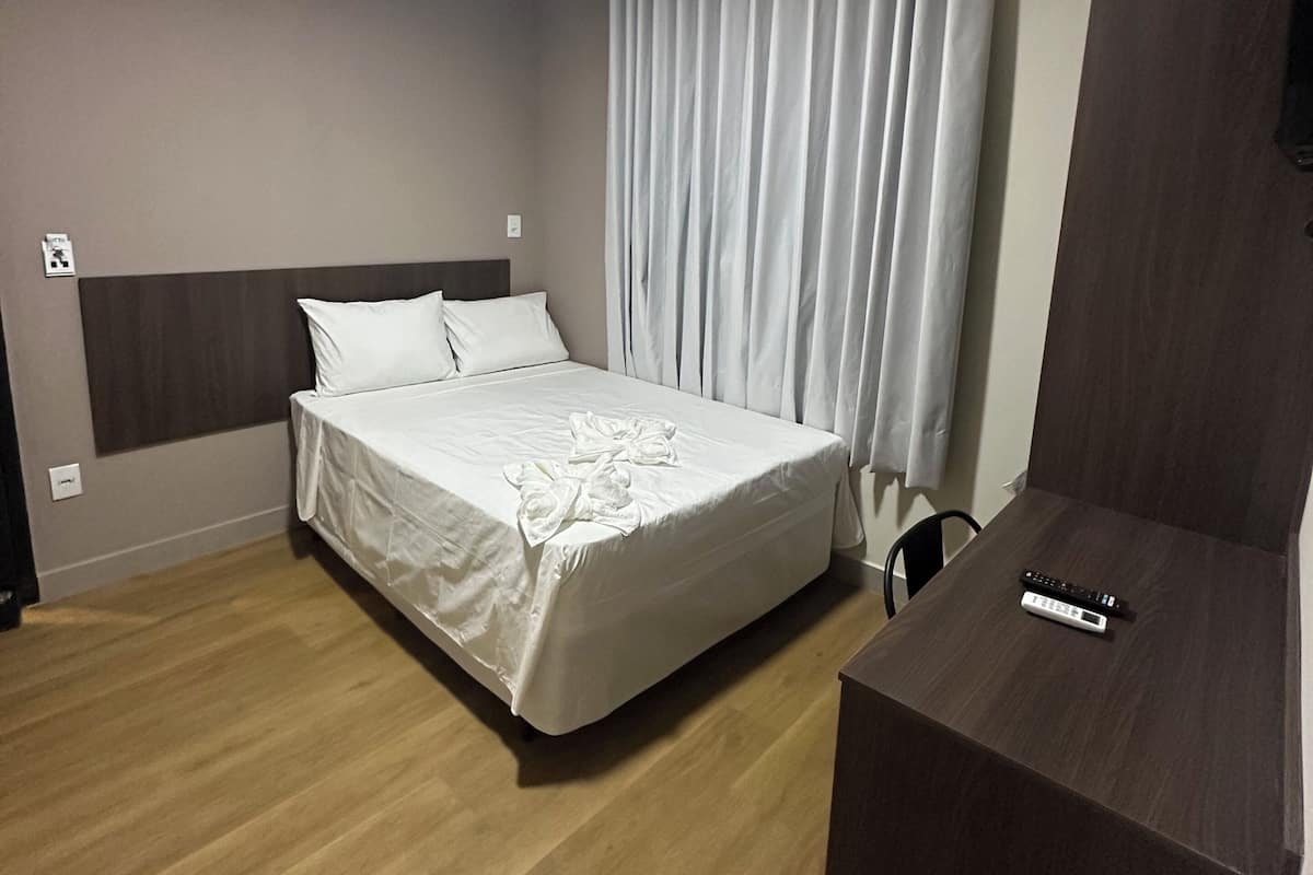 Ein Hotelzimmer mit Bett, Schreibtisch und Fernseher.