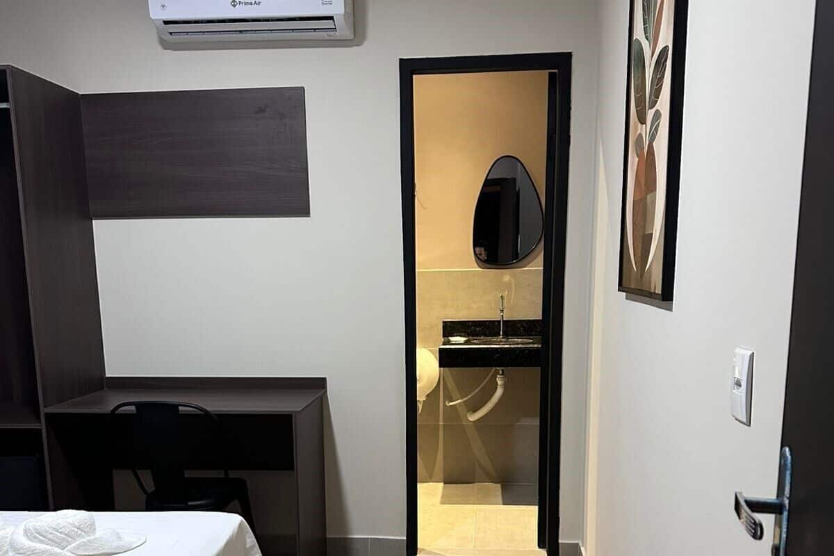 Ein Hotelzimmer mit Bett, Schreibtisch, Kleiderschrank und einem durchgegangenen Tür sichtbaren Badezimmer.