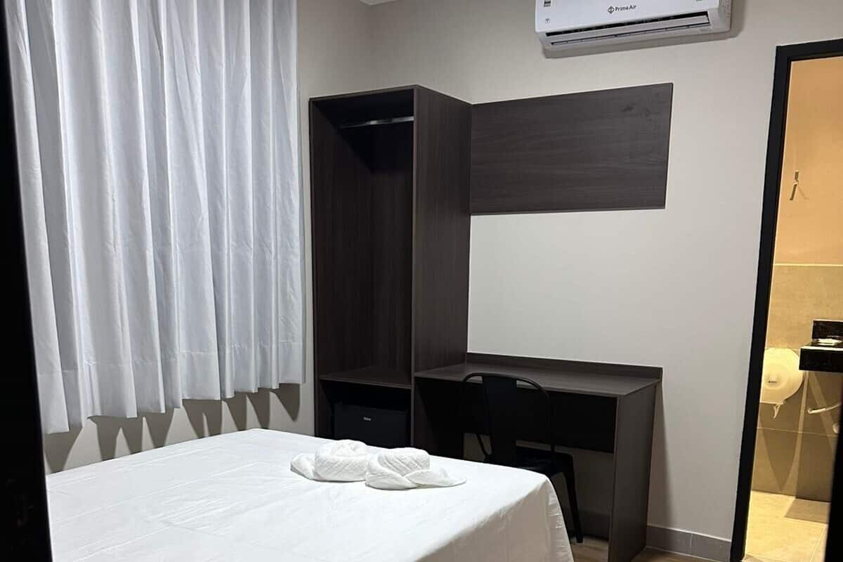 Ein Hotelzimmer mit einem Bett, einem Schreibtisch und einer Klimaanlage.