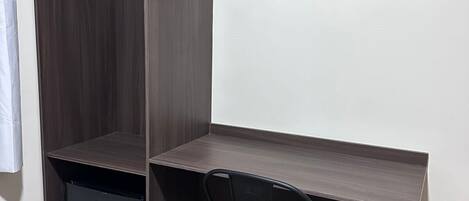 Habitación de esquina con escritorio integrado, una silla y un refrigerador pequeño.