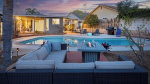 A backyard with a swimming pool, outdoor seating, and a house. - California Dreamin by Avantstay Private Pool + Fire Pit Near the Beach (Carlsbad)