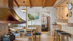 A cozy kitchen with wooden cabinets, a dining area with a table and chairs, and a decorative plant. - California Dreamin by Avantstay Private Pool + Fire Pit Near the Beach (Carlsbad)