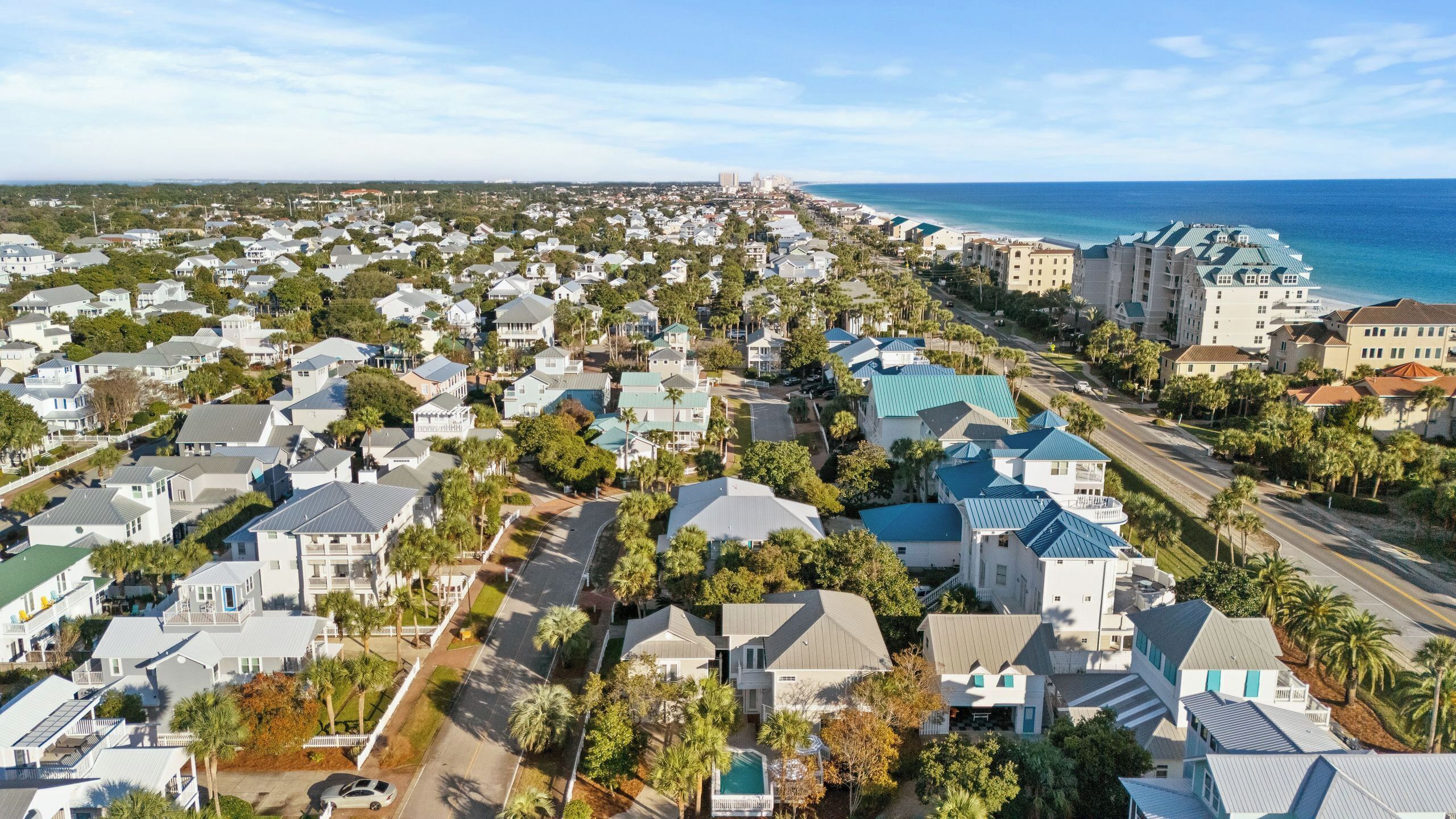 A coastal residential area with houses, a beach, and a clear sky.