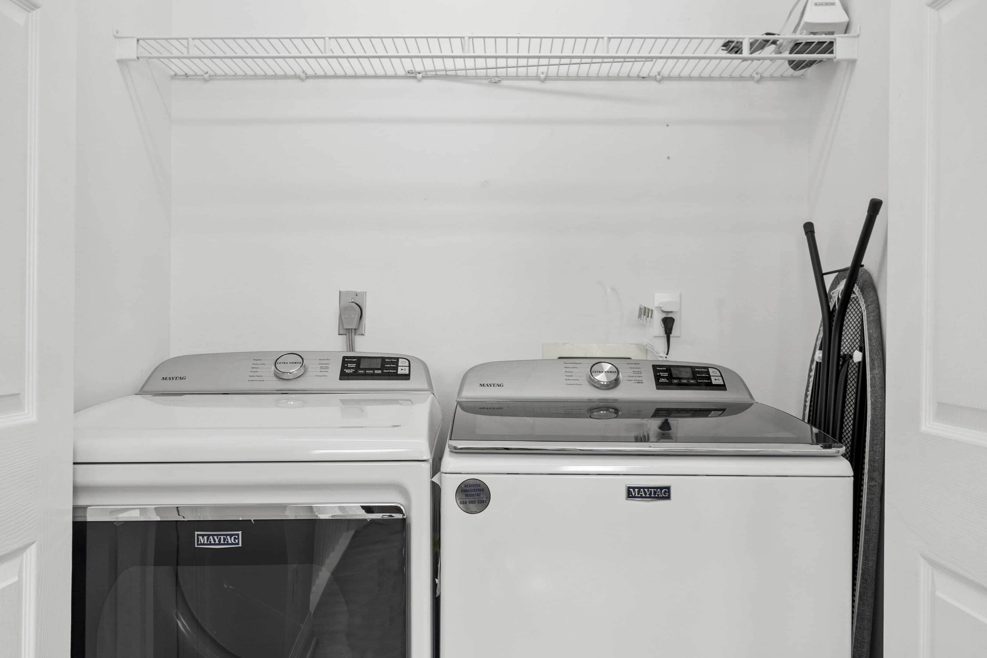 A laundry room with two Maytag washers and dryers, a power outlet, and a rack for hanging clothes.
