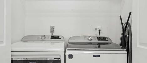 A laundry room with two Maytag washers and dryers, a power outlet, and a rack for hanging clothes.