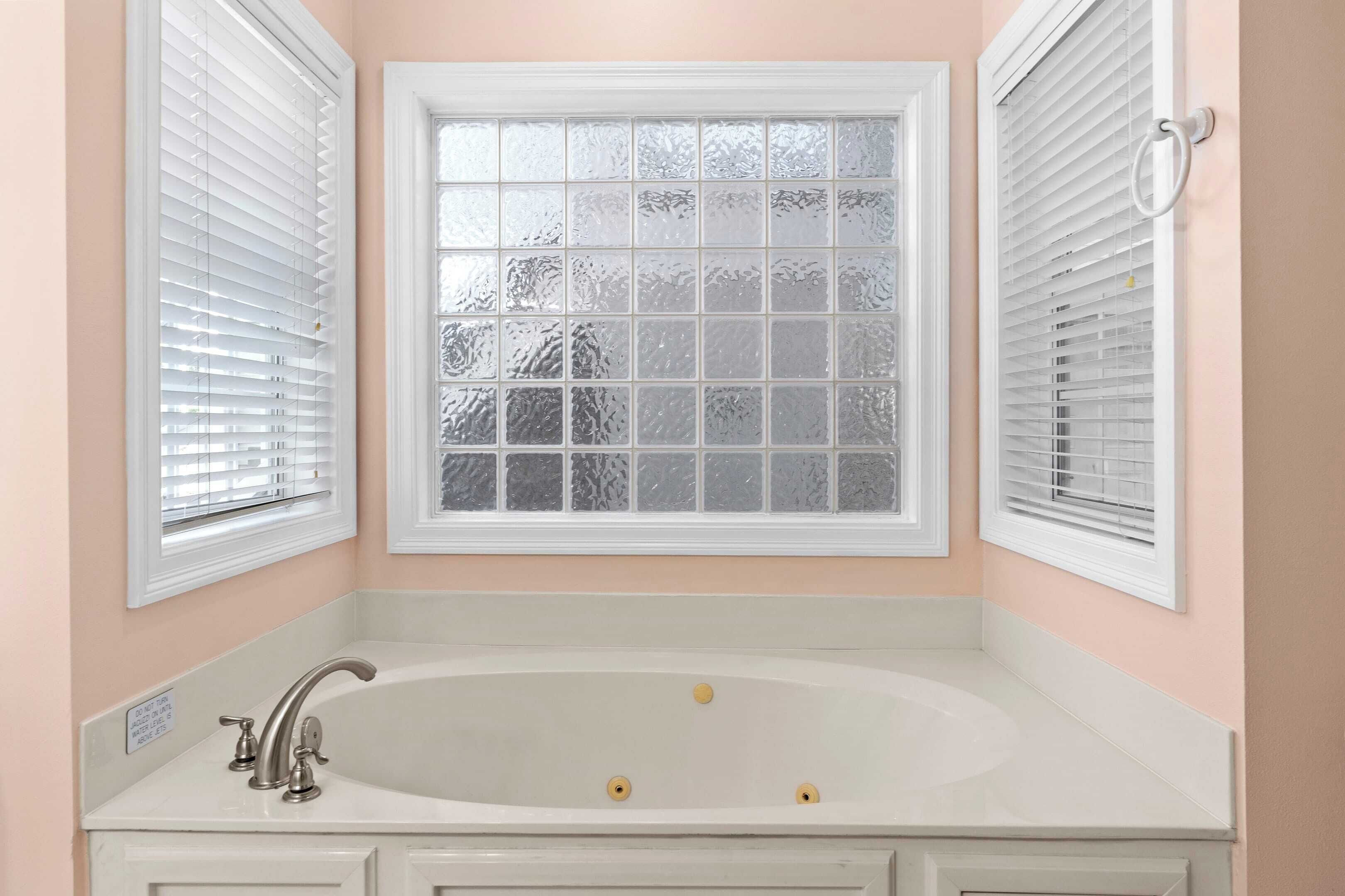 Ein Badezimmer mit freistehender Badewanne, Milchglasfenster und weißen Armaturen.