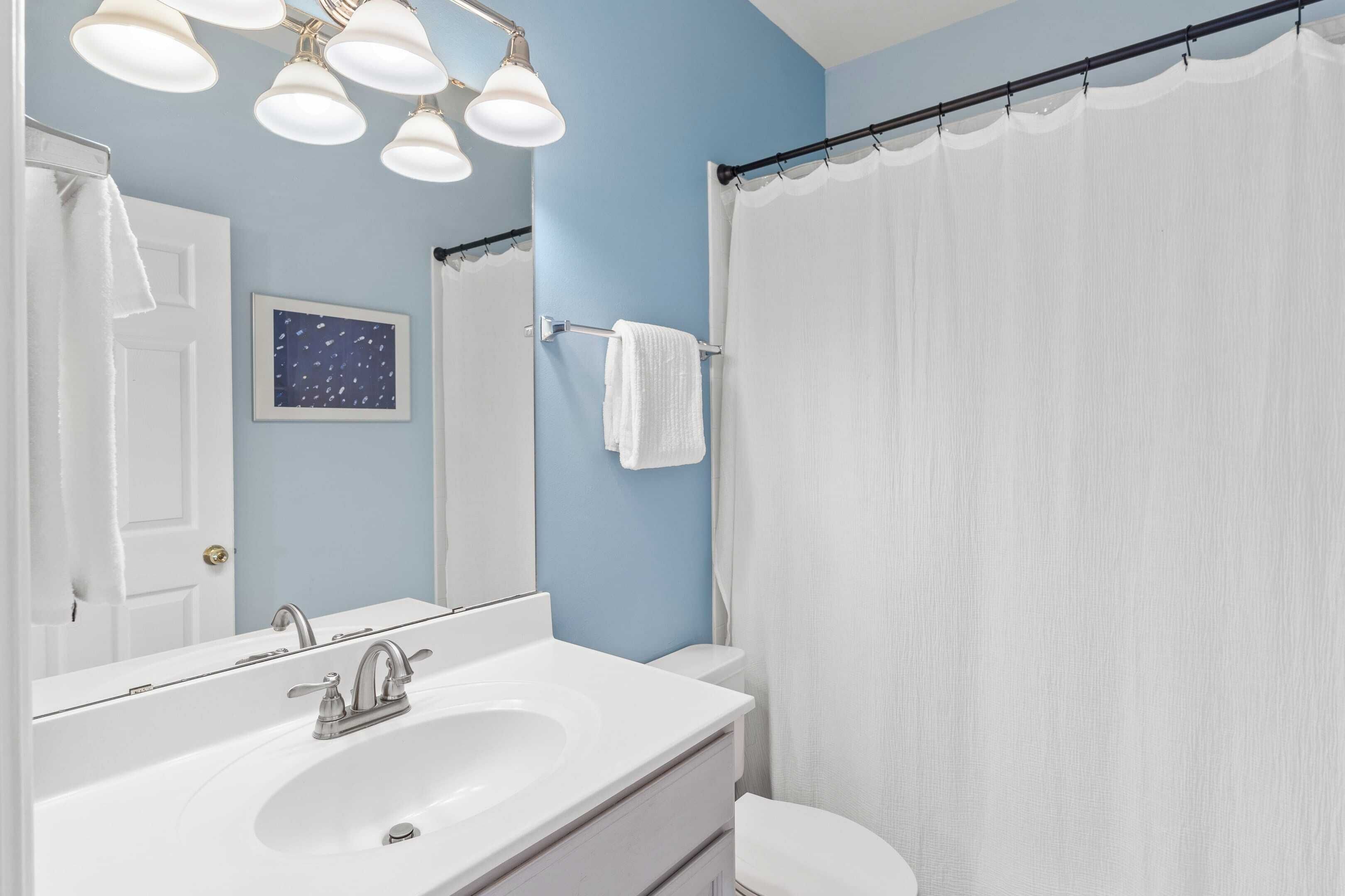 A bathroom with a white sink, a mirror, and a shower curtain.