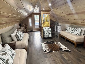 A cozy loft bedroom with a sloped ceiling, wooden flooring, a large window, and a view of the outdoors. - Spruce House - Beautiful Remodel - Great Downtown Location! (Lake City)