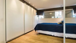 A bedroom with a bed, a window, and a wooden floor. - Spacious, modern and cozy apartment very well located (Itaim Bibi São Paulo)