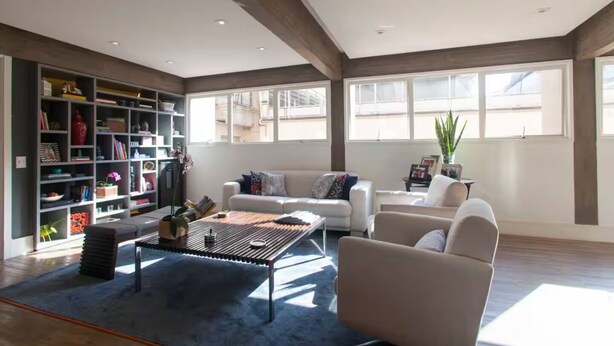 A spacious living room with a large bookshelf, a coffee table, and a sofa. - Spacious, modern and cozy apartment very well located (Itaim Bibi São Paulo)