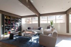 A spacious living room with a large bookshelf, a coffee table, and a sofa. - Spacious, modern, and cozy apartment in a great location (Itaim Bibi São Paulo)