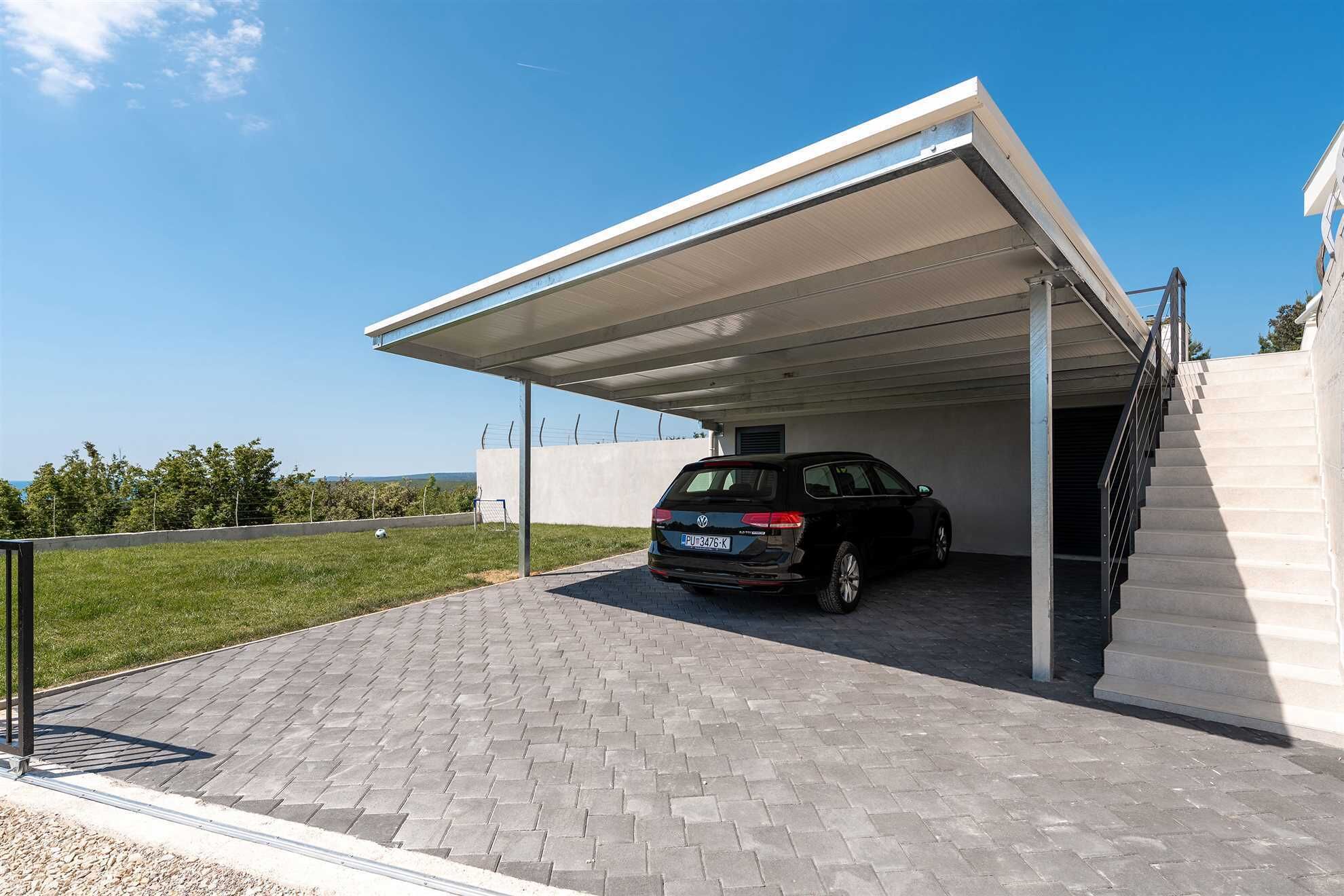 Eine moderne Autohaus mit einem schwarzen SUV auf dem gepflasterten Weg und blauem Himmel.