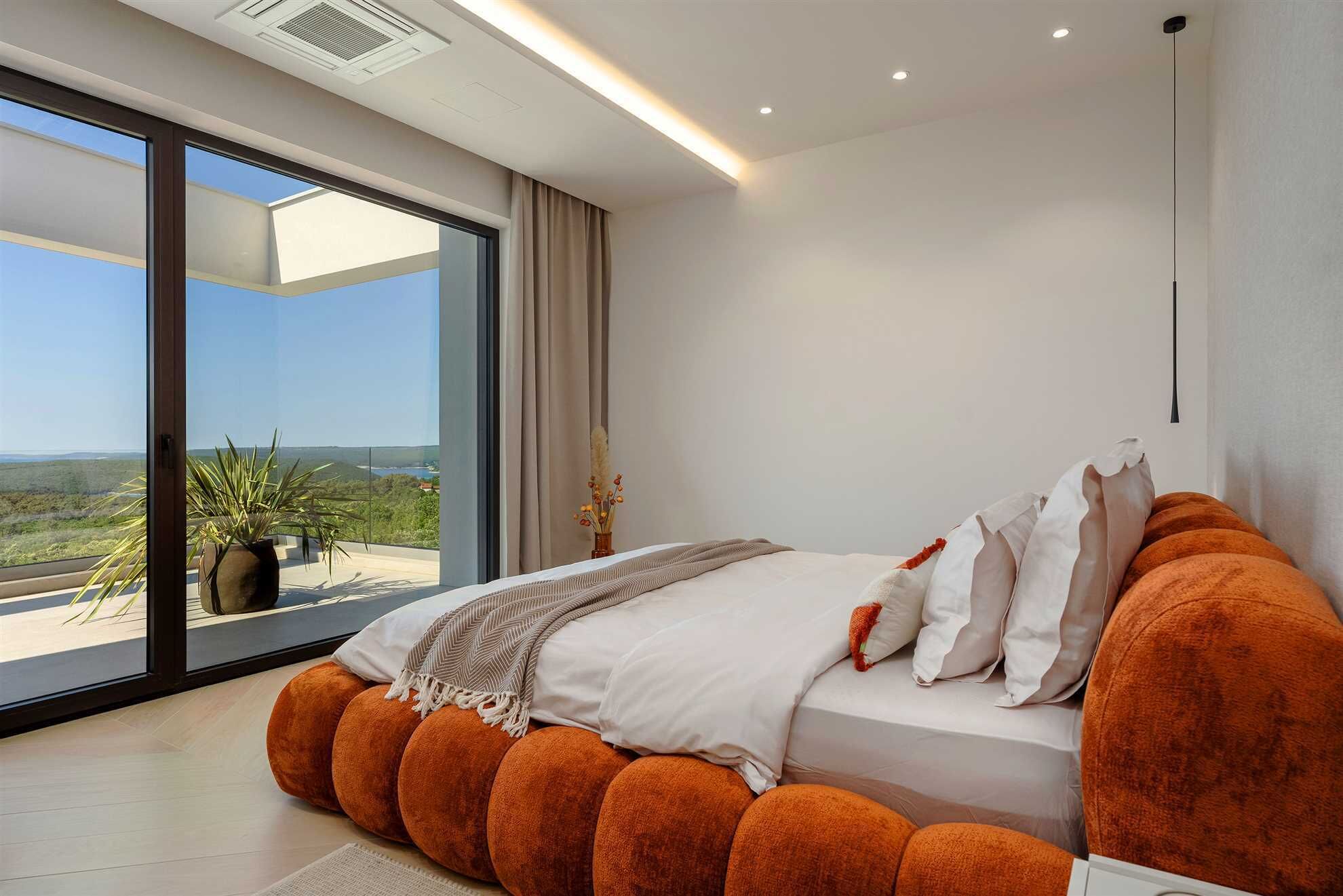 Un dormitorio moderno con una cama grande, vistas al exterior e iluminación empotrada en el techo.