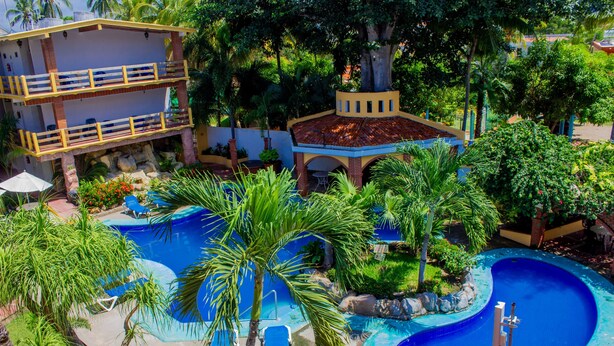 Ein Resort mit Pool, Palmen und einem mehrstöckigen Gebäude mit Balkonen.