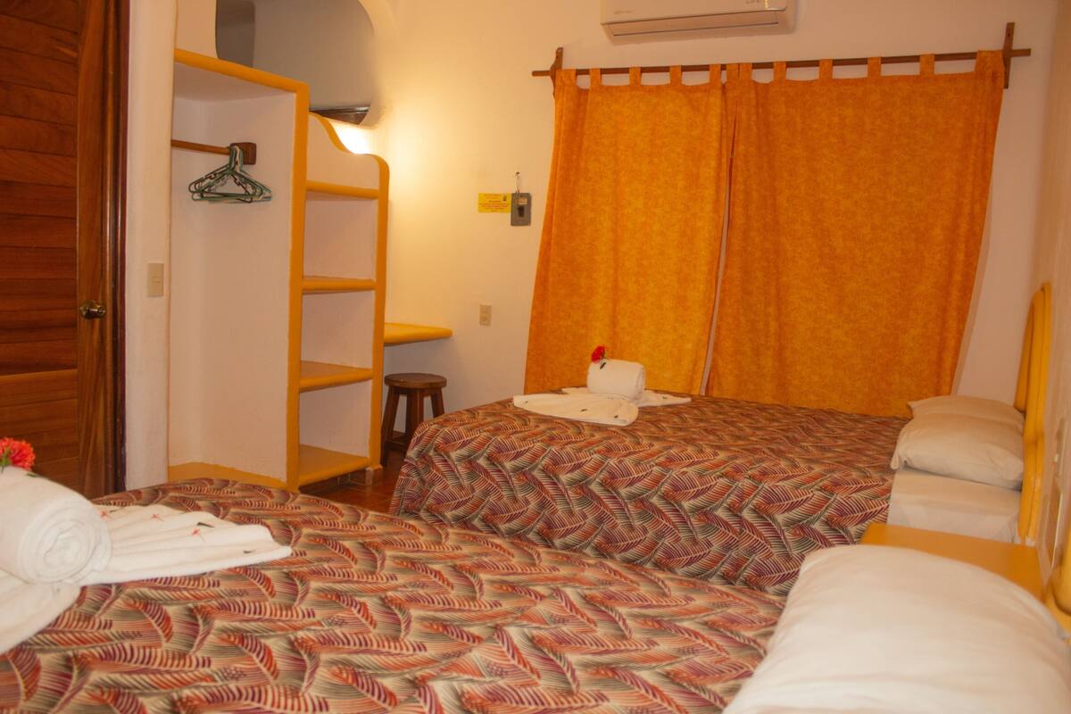 Un dormitorio con dos camas, un armario de madera, un perchero y un taburete pequeño.