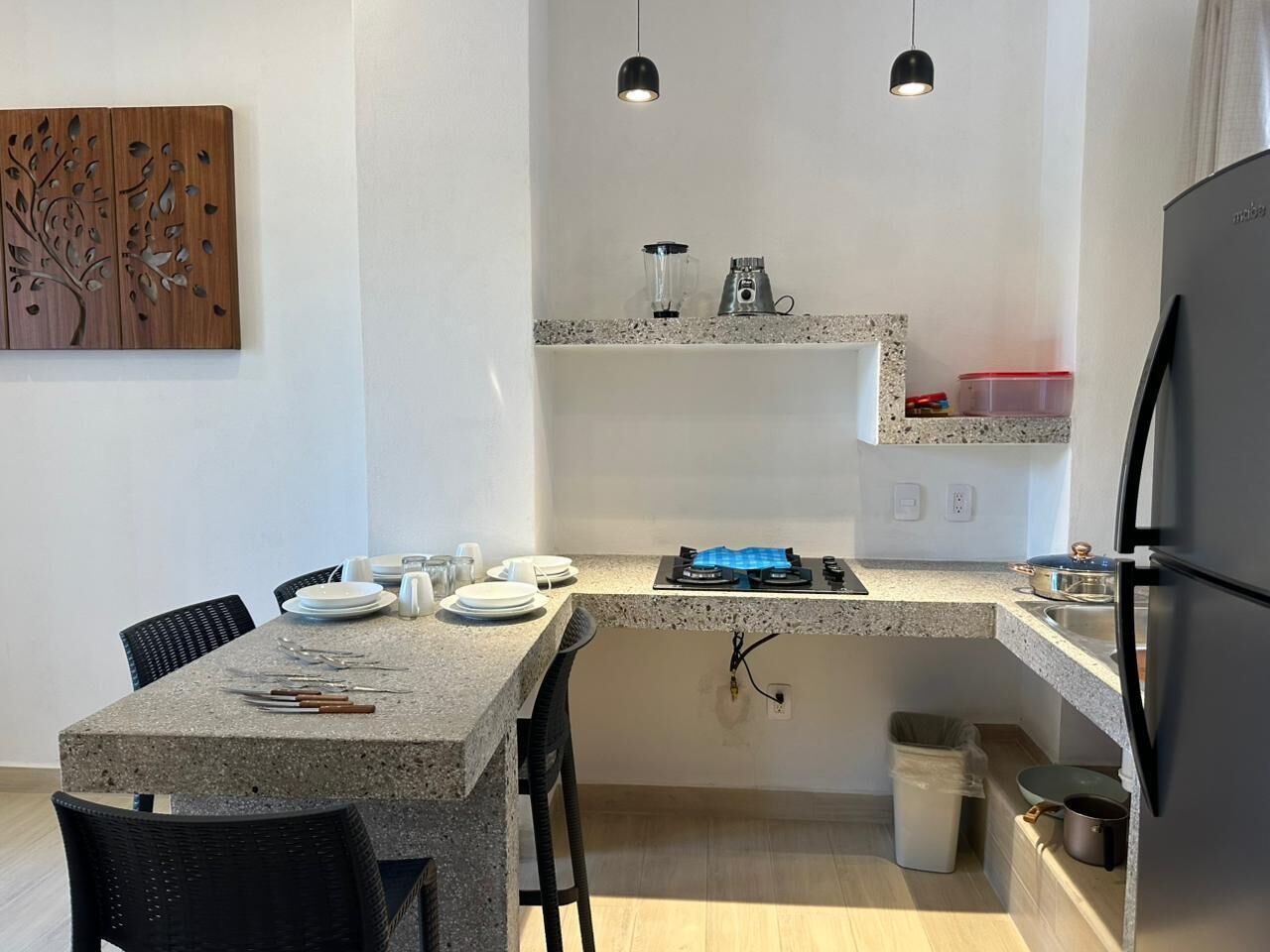 Una cocina compacta con encimera de granito, estufa a gas, refrigerador y un comedor con sillas y una mesa lista para cuatro.