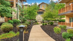 A pathway leading through a landscaped area with stone walls and various shrubs.
