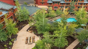 A hotel with multiple buildings, a pool, and a landscaped garden with a pathway and seating area.