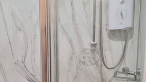 Un baño con ducha de vidrio, inodoro y pared de mármol.