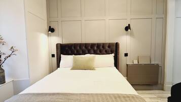 A neatly arranged bedroom with a tufted headboard, a bedside table, and a lamp.