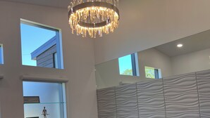 A modern bedroom with a large bed, a chandelier, and a view of the outside. - MoonBeam: Spacious and Modern Home in the countryside near Stockton Lake.  (Stockton)