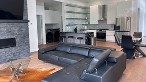 A modern living room with a sectional sofa, a glass coffee table, and a leather ottoman. - MoonBeam: Spacious and Modern Home in the countryside near Stockton Lake.  (Stockton)