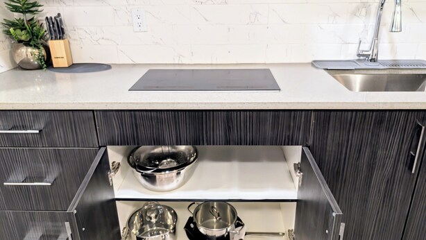A kitchen with a white marble backsplash, a stainless steel sink, and a built-in drawer with cookware. - Luxury and Modern 2 bedroom suite (Balzac)