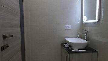Une salle de bain moderne avec un grand miroir, un lavabo et un meuble de rangement.