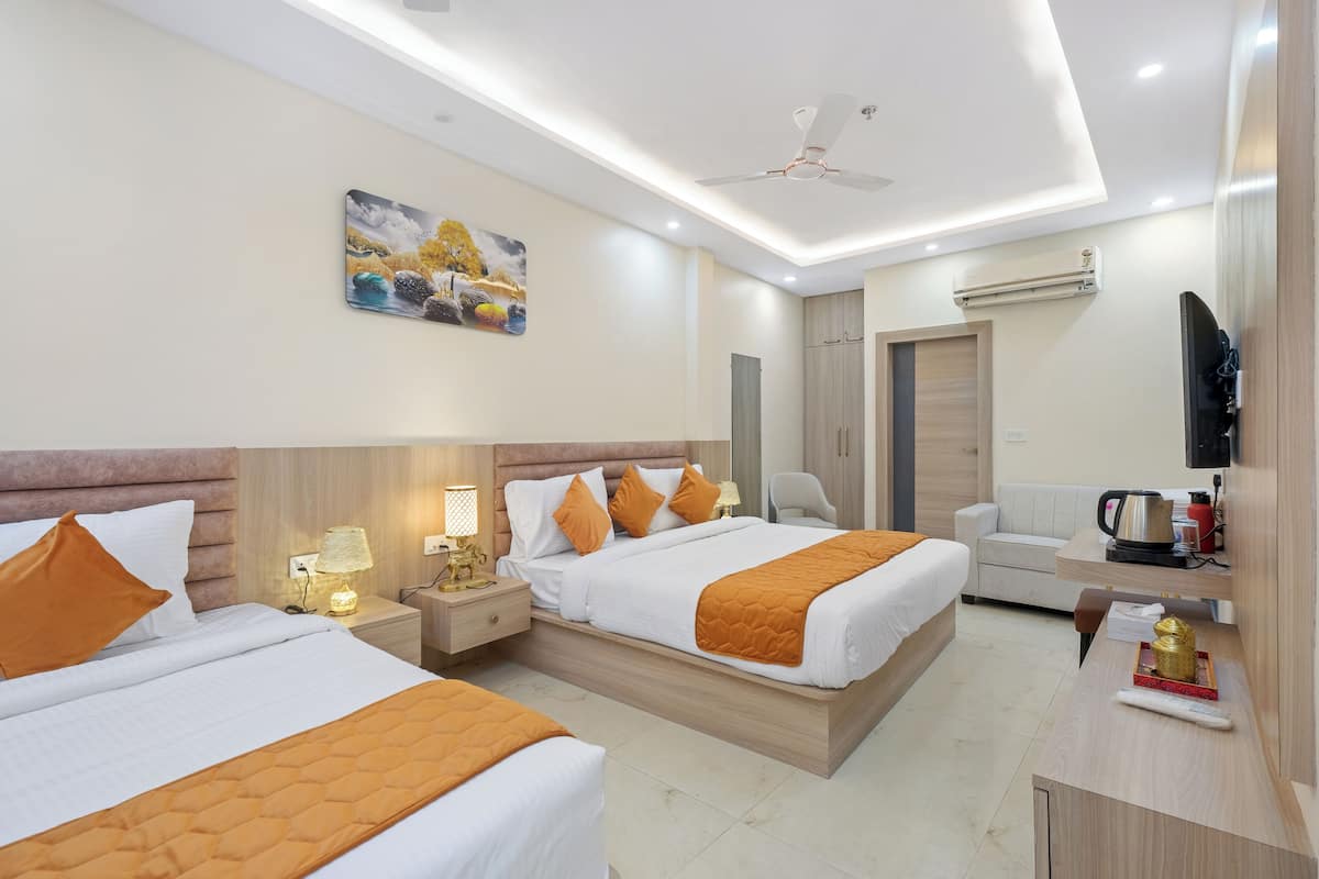 Quarto de hotel com duas camas, uma escrivaninha, uma cadeira, uma televisão e um quadro na parede.