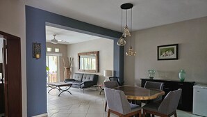 A dining area with a round wooden table, grey upholstered chairs, a black sofa, and a black cabinet.