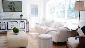 Ein helles Wohnzimmer mit einer Couch, einem Hocker und einer Lampe.