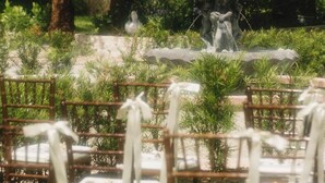 Ein Garten mit einem Brunnen, umgeben von viel Grün und Bäumen.