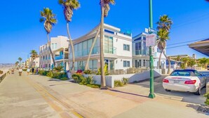 A modern building with large windows and a flat roof, located on a sunny street with palm trees. - Coastal Haven (San Diego)