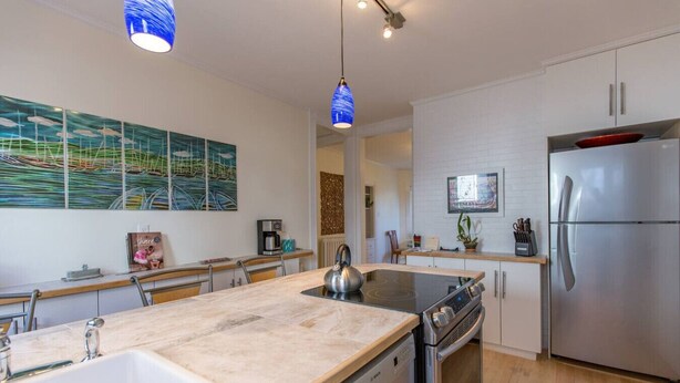 Una cocina moderna con una isla central, electrodomésticos de acero inoxidable y una obra de arte contemporánea.
