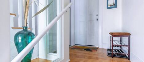 A staircase with a glass railing, a wooden floor, a door labeled 'B', and a small wooden table with shelves.
